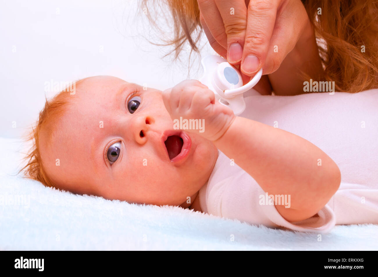 Young mother trying to give baby`s dummy to newborn baby Stock Photo